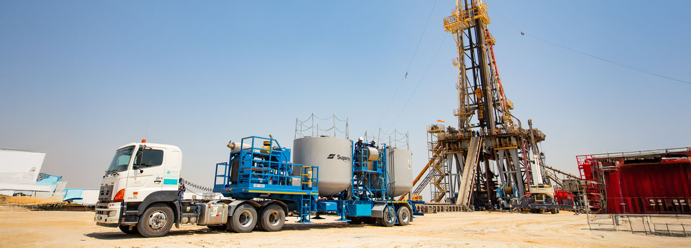 A Superior Cementing truck parked in front of an oil derrick
